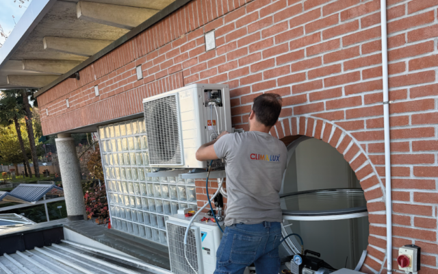 Tecnico Climalux installa unità esterna climatizzatore Daikin su facciata in Ticino